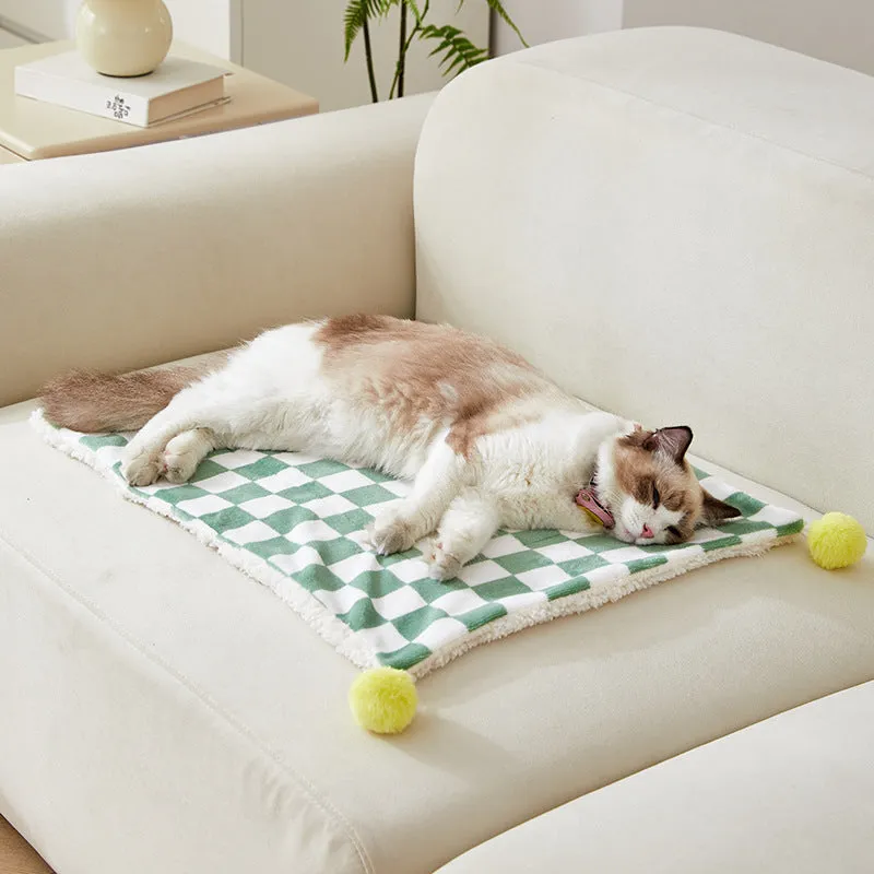 Soft plaid pattern pet blanket with fur ball decoration on a sofa