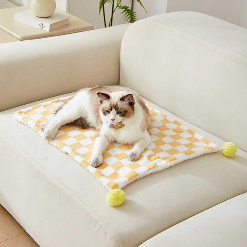 Soft plaid pattern pet blanket with fur ball decoration on a sofa
