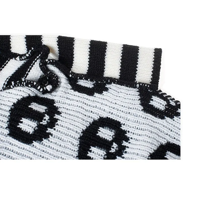 Black skull-pattern acrylic knit dog sweater on a pet, front view, with ribbed neckline and pullover style