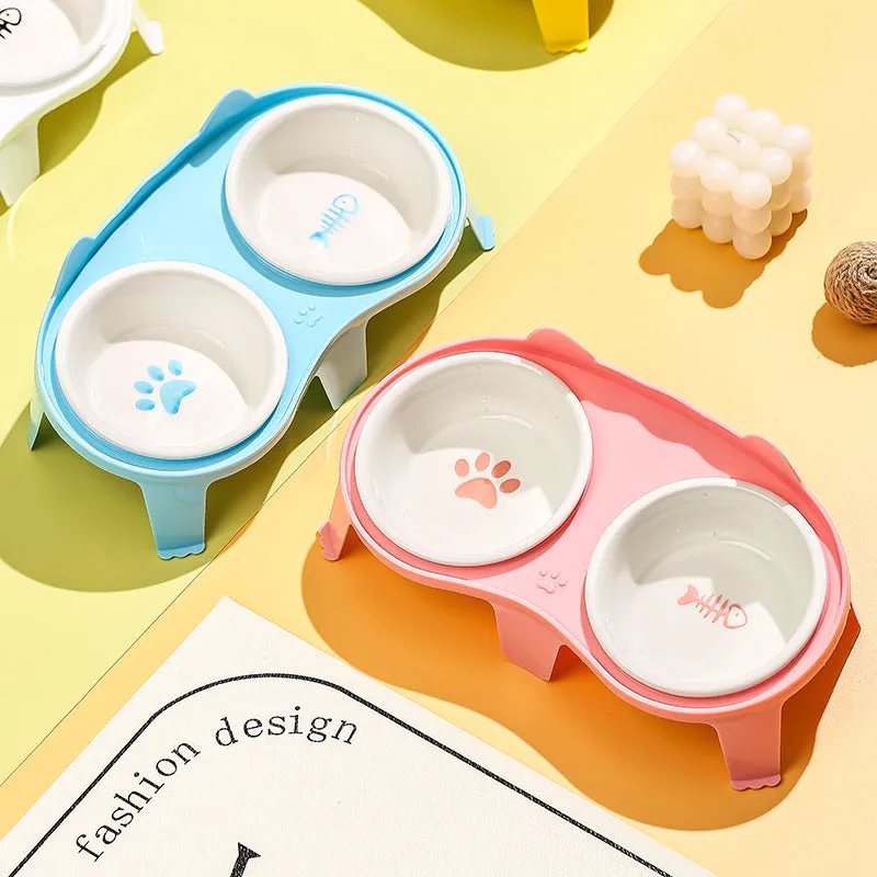Blue ceramic cat food and water bowls in a white elevated plastic stand with a hook.