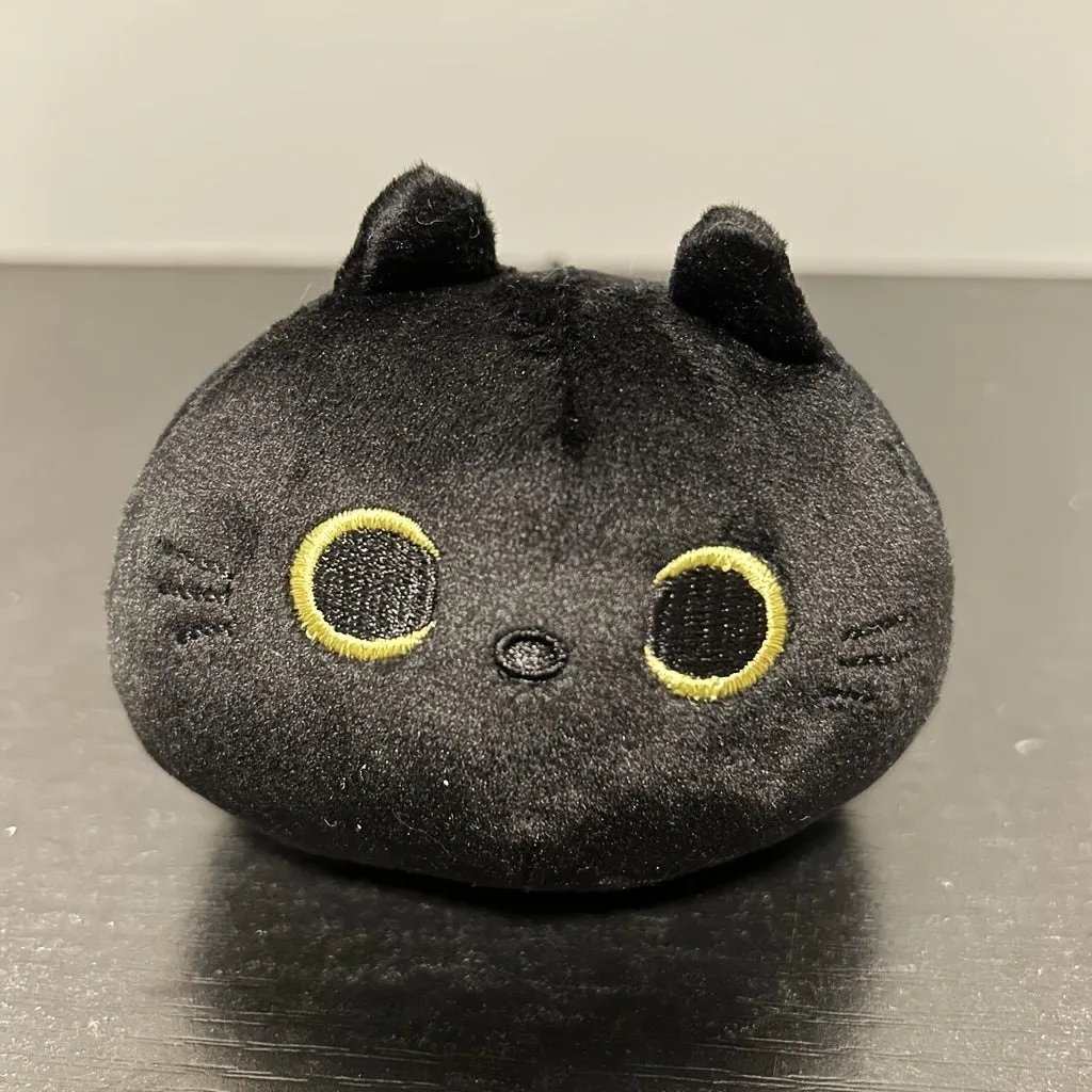 Fluffy black cat plush toy stuffed animal pillow cushion on a neutral background