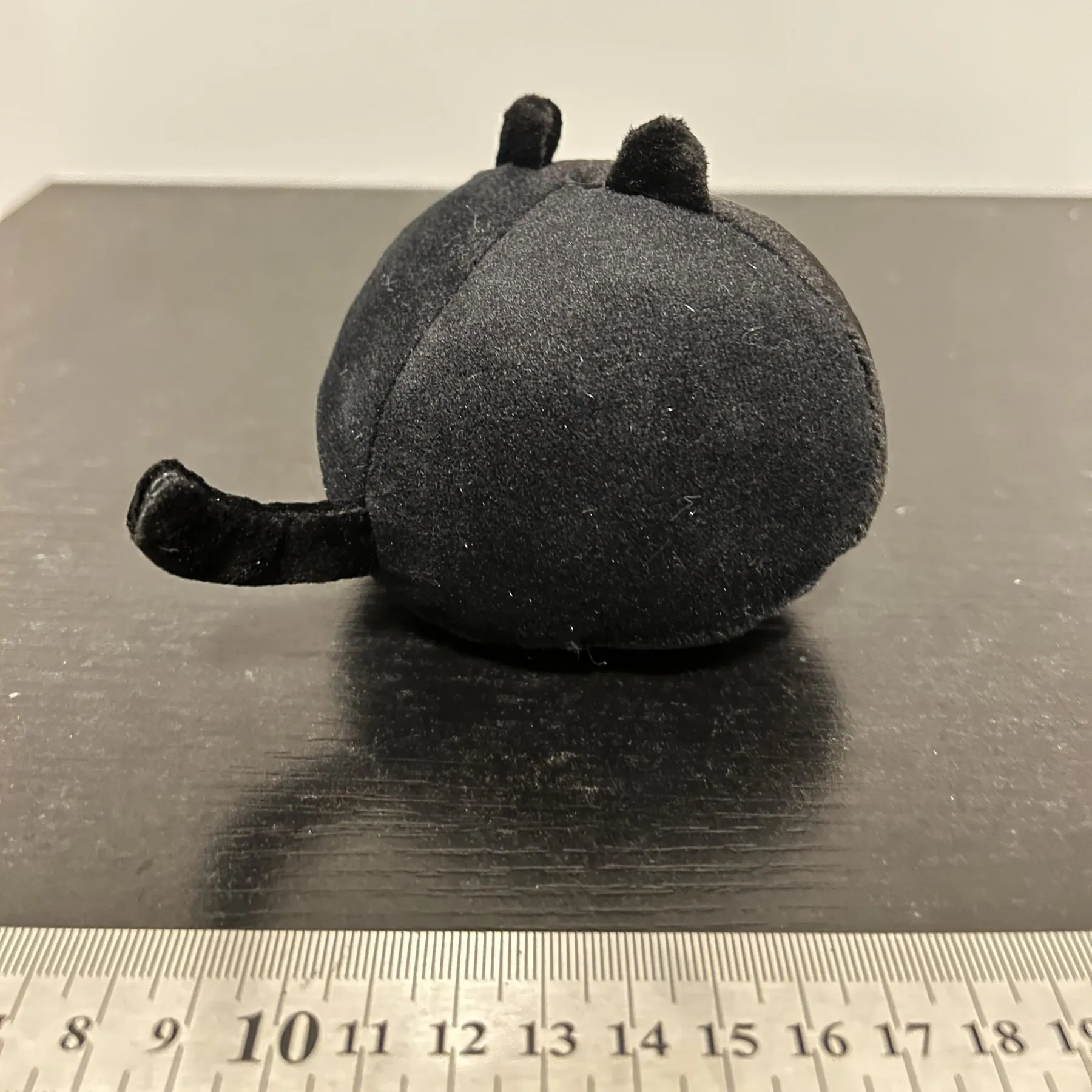 Fluffy black cat plush toy stuffed animal pillow cushion on a neutral background