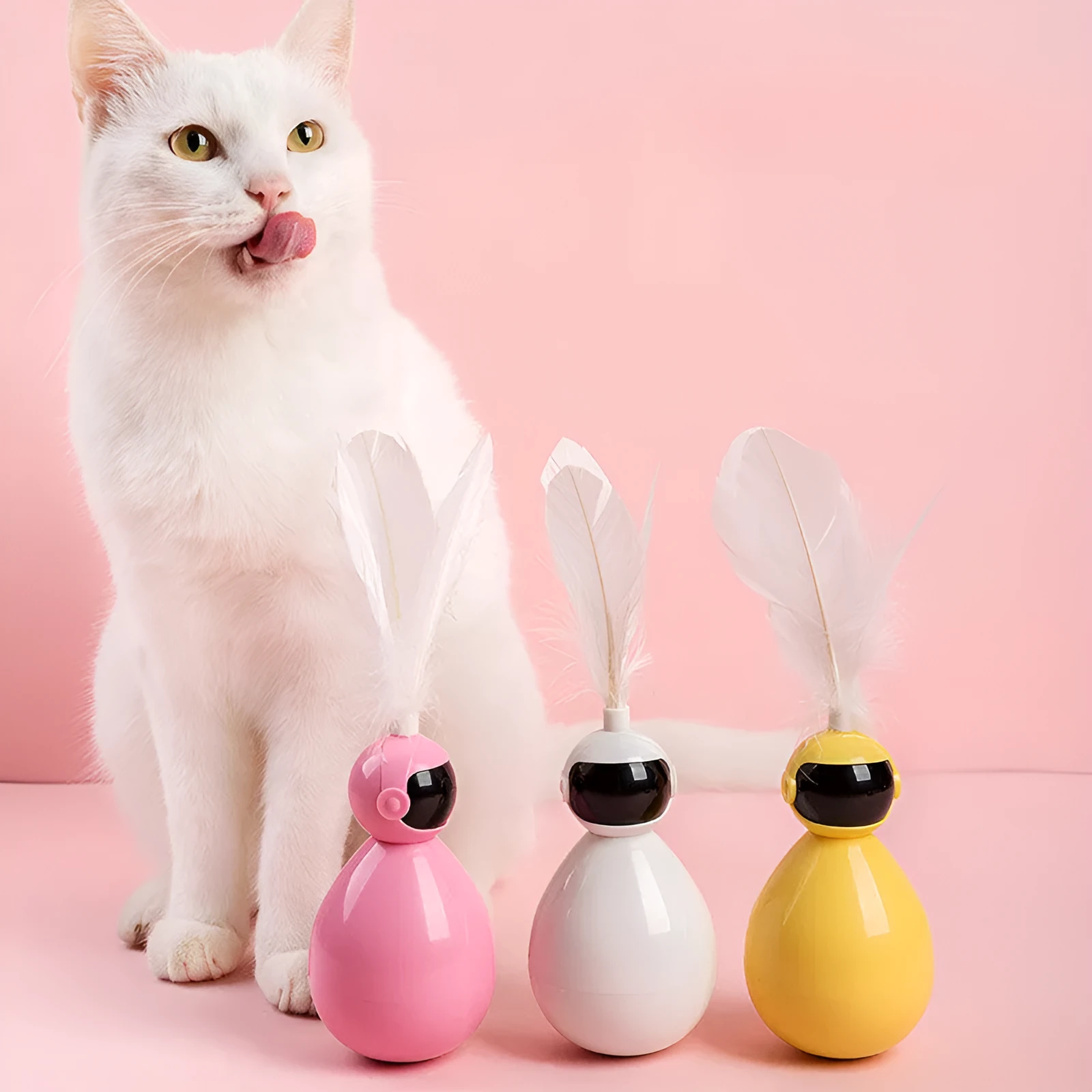 Tumbler cat toy in white with three replacement feathers on a light background