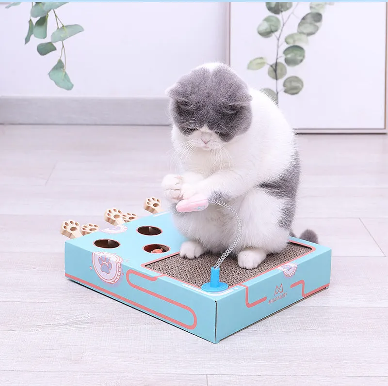 Blue cat toy teaser whack-a-mole game on floor, 36x26x6cm, cardboard and wood construction.