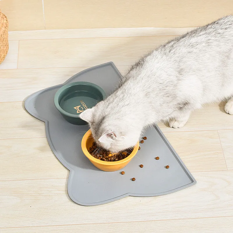 Blue cat head shaped silicone pet feeding mat placed under food and water bowls.