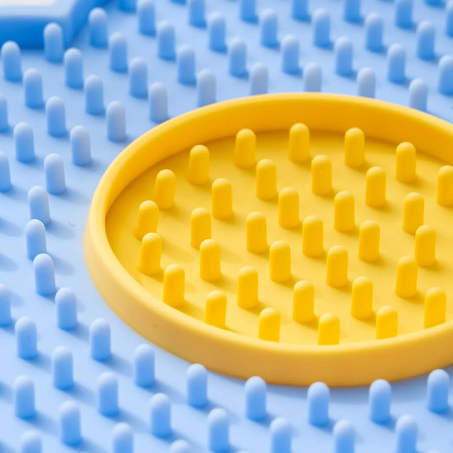 Flower-shaped silicone pet lick mat with suction cups on a smooth surface in assorted colours.