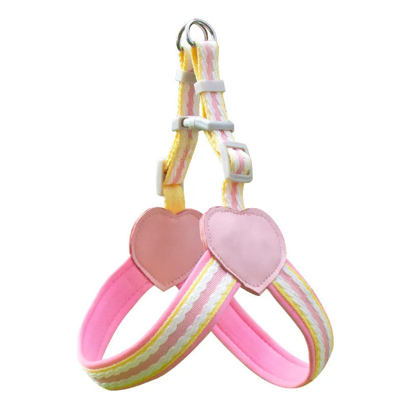 A dog wearing a pink nylon chest strap vest harness with an attached hand holding rope.