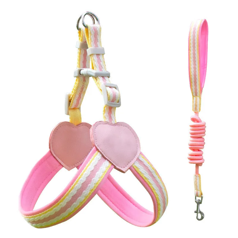 A dog wearing a pink nylon chest strap vest harness with an attached hand holding rope.