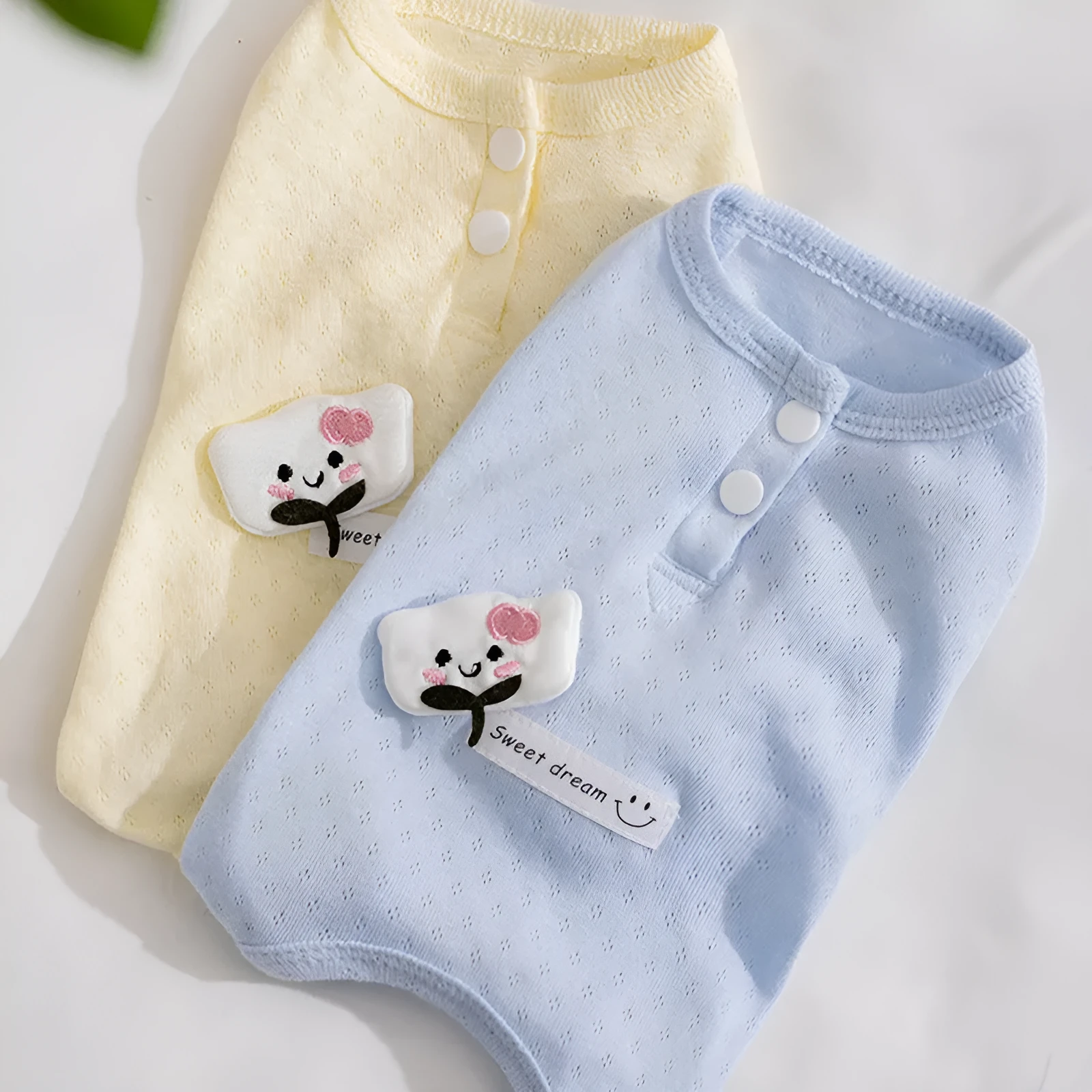 Soft yellow mesh pet shirt with cartoon cat patch and button closure on a small dog or cat