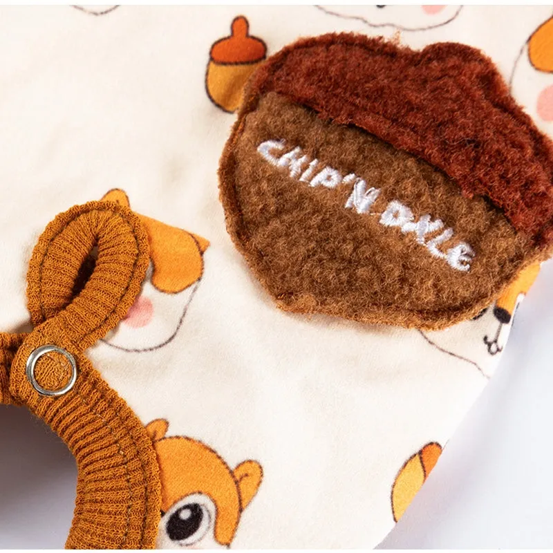 Small dog wearing Chip 'n' Dale themed cream onesie with yellow trim and embroidered acorn pocket