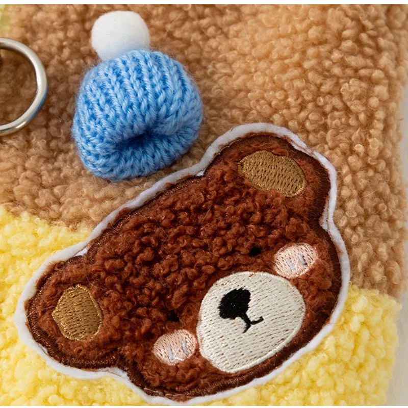 Small dog wearing a blue fleece jacket with bear embroidery and plaid pockets