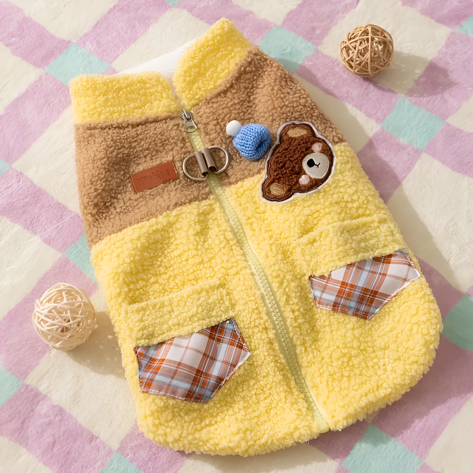 Small dog wearing a blue fleece jacket with bear embroidery and plaid pockets