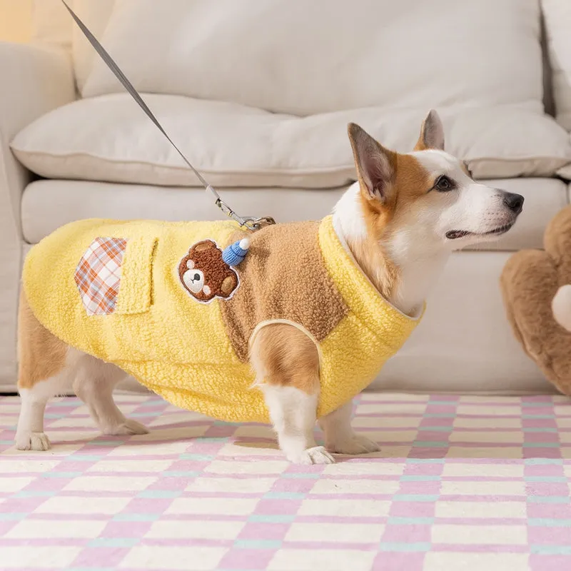 Small dog wearing a blue fleece jacket with bear embroidery and plaid pockets