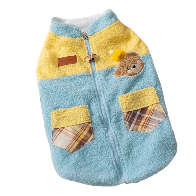 Small dog wearing a blue fleece jacket with bear embroidery and plaid pockets