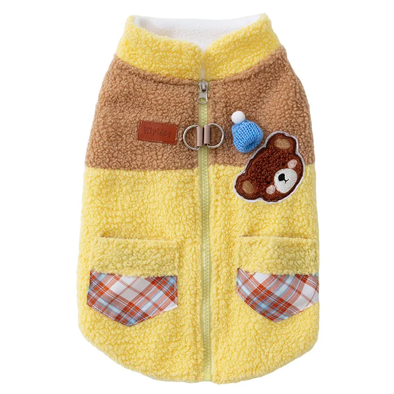 Small dog wearing a blue fleece jacket with bear embroidery and plaid pockets