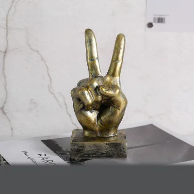 Resin hand gesture ornament in metallic finish on wooden surface