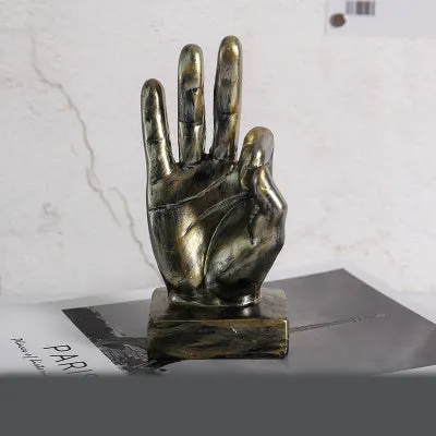 Resin hand gesture ornament in metallic finish on wooden surface