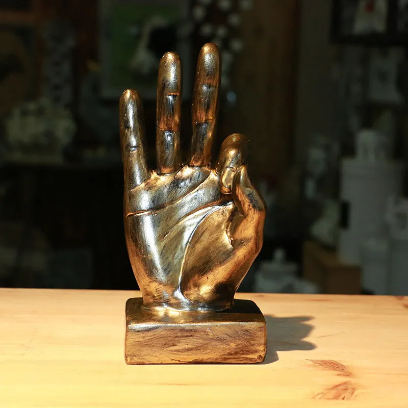 Resin hand gesture ornament in metallic finish on wooden surface