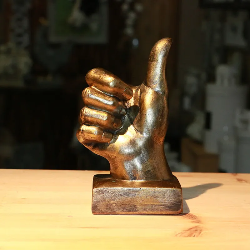 Resin hand gesture ornament in metallic finish on wooden surface