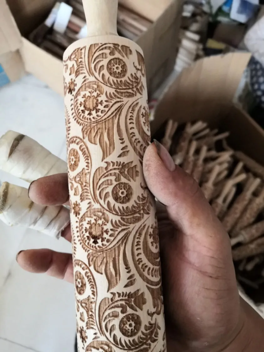 Wooden rolling pin with embossed Christmas patterns, 45cm long, on a kitchen worktop.