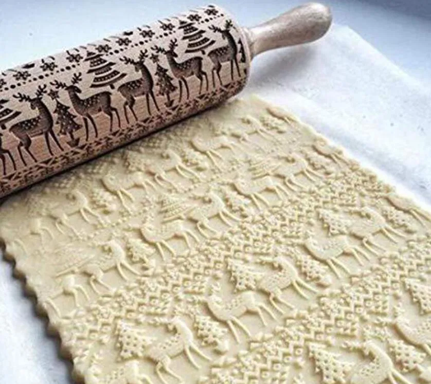 Wooden rolling pin with embossed Christmas patterns, 45cm long, on a kitchen worktop.
