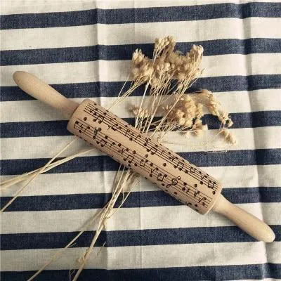 Wooden rolling pin with embossed Christmas patterns, 45cm long, on a kitchen worktop.