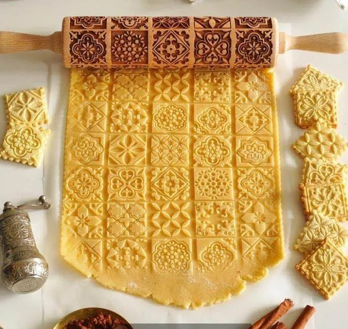 Wooden rolling pin with embossed Christmas patterns, 45cm long, on a kitchen worktop.