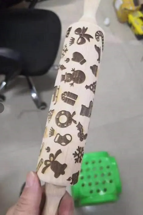 Wooden rolling pin with embossed Christmas patterns, 45cm long, on a kitchen worktop.