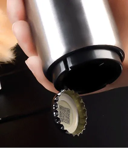 Stainless steel automatic bottle opener on a table, showing its compact size and press-down design.