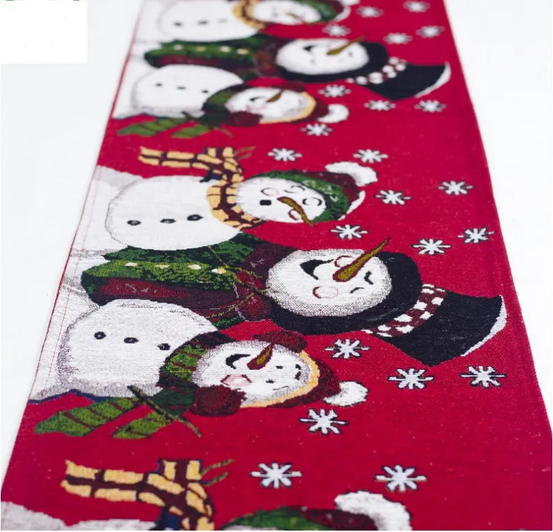 Red, white, and green Christmas table runner with elk and snowman print on a wooden dining table.