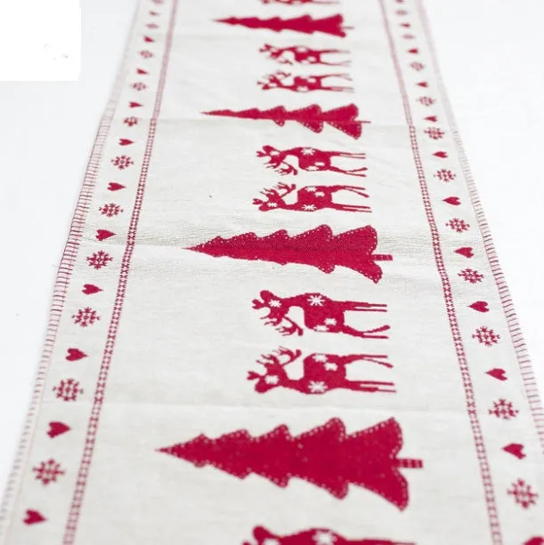 Red, white, and green Christmas table runner with elk and snowman print on a wooden dining table.