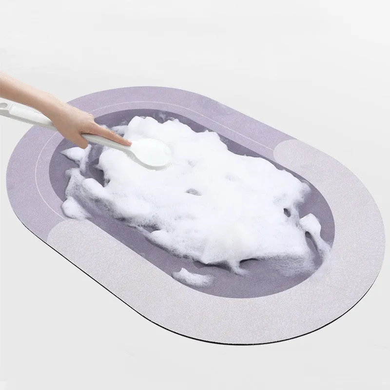 Oval grey polyester door mat with textured rubber non-slip backing on a wooden floor.