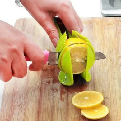 Green plastic fruit and vegetable cutting holder with slicing grid, measuring 18.5 cm.