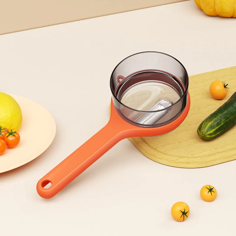 Light green kitchen peeler with a small orange storage bucket attached underneath the blade.