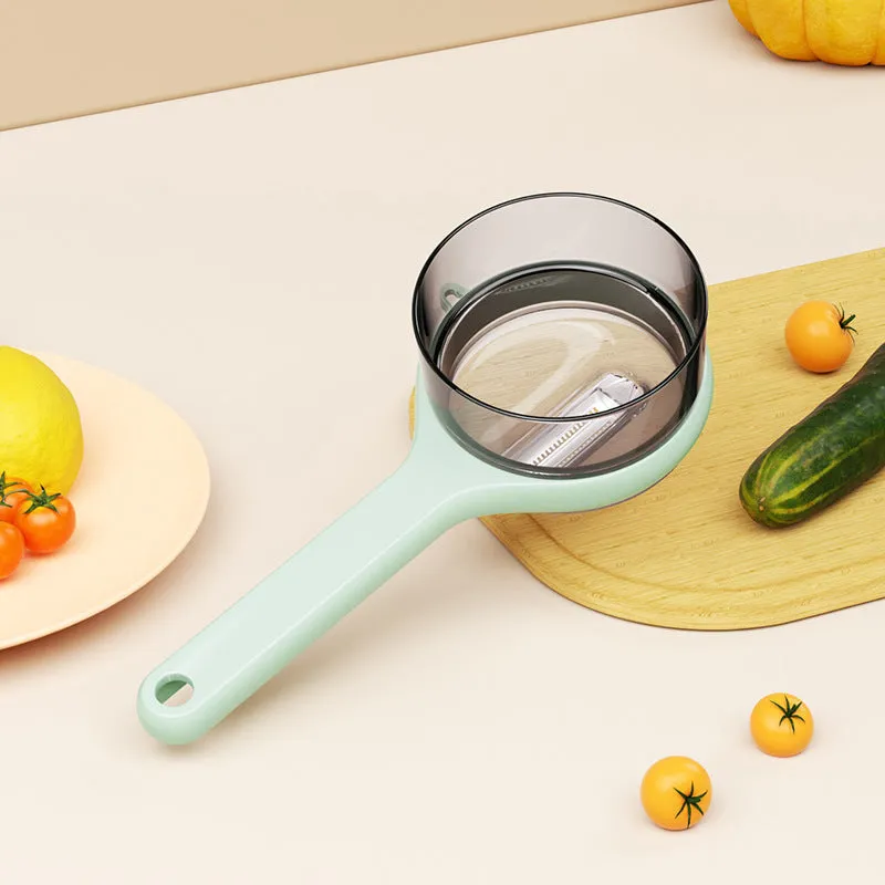 Light green kitchen peeler with a small orange storage bucket attached underneath the blade.