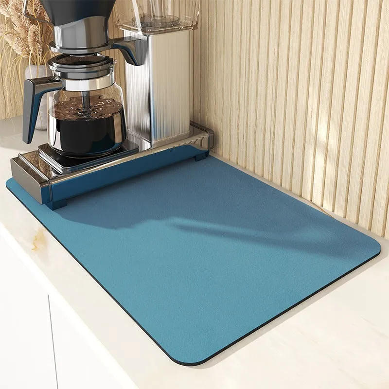 Black square rubber-backed kitchen drying mat on a countertop next to a coffee cup