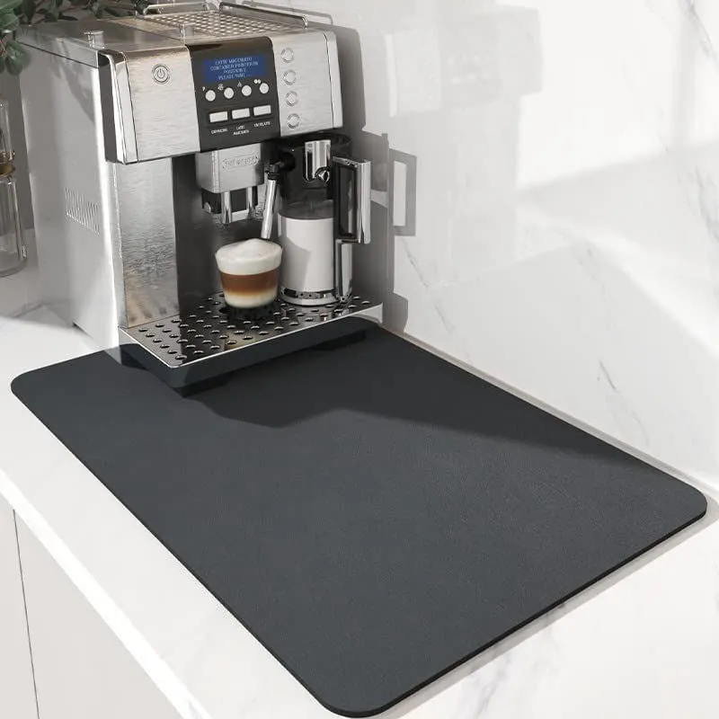 Black square rubber-backed kitchen drying mat on a countertop next to a coffee cup