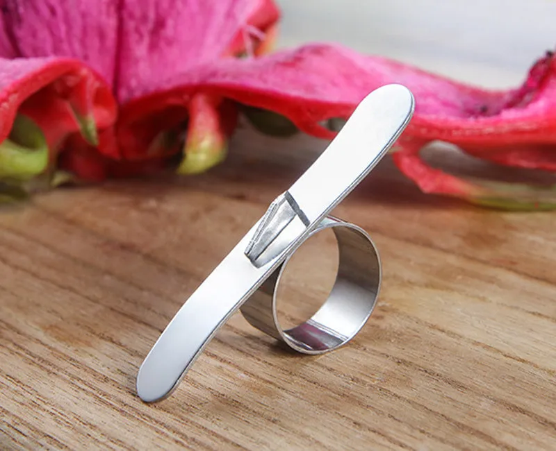 Silver stainless steel citrus fruit peeler with a ring-shaped handle on a kitchen surface.