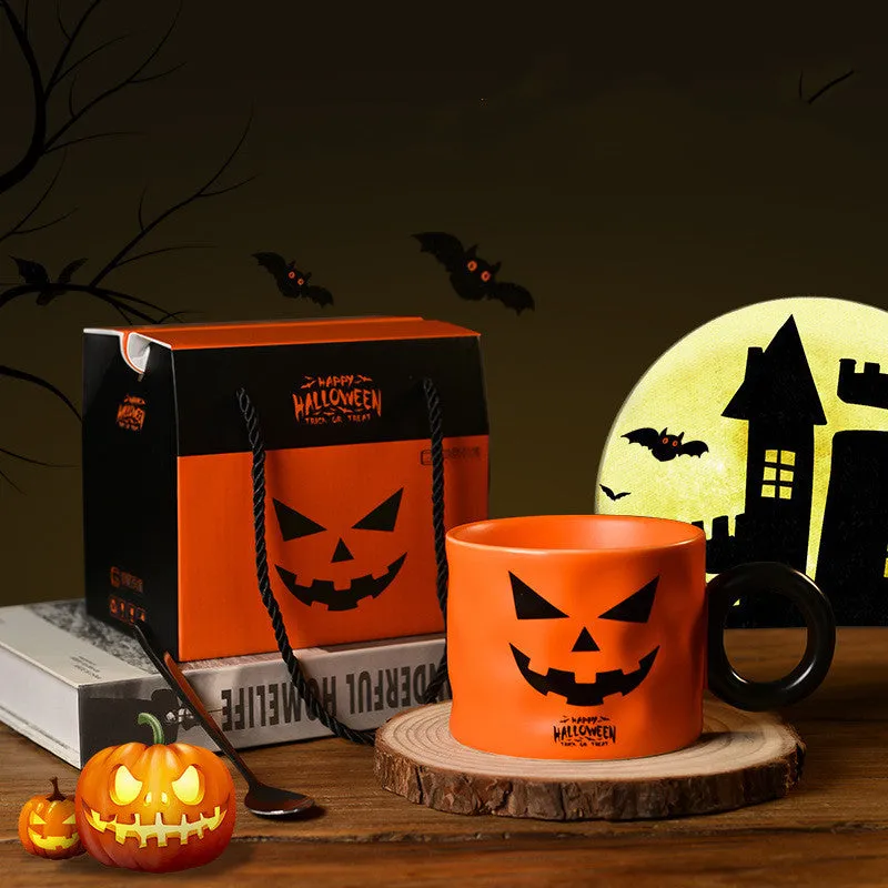 Orange ceramic Halloween pumpkin cup with handle beside dessert spoon in gift box