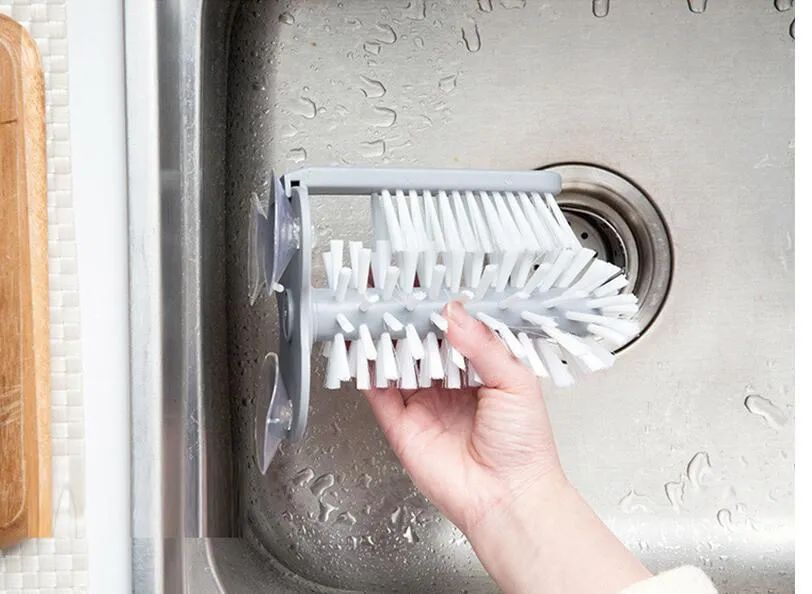 Grey kitchen cleaning brush with two brush heads and suction cups for wall mounting