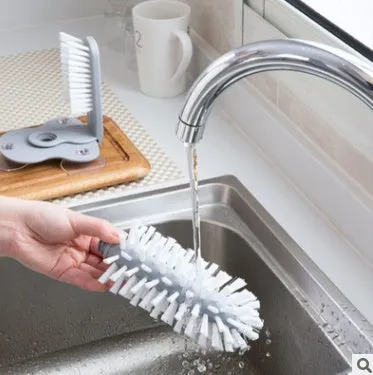 Grey kitchen cleaning brush with two brush heads and suction cups for wall mounting