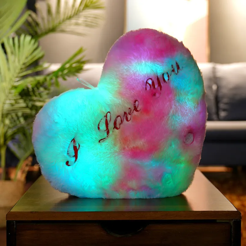 Colourful glowing five-pointed star plush pillow on a dark background, illuminated from within.