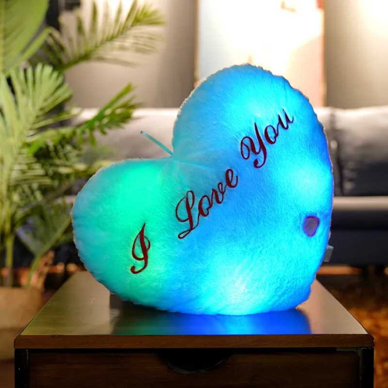 Colourful glowing five-pointed star plush pillow on a dark background, illuminated from within.