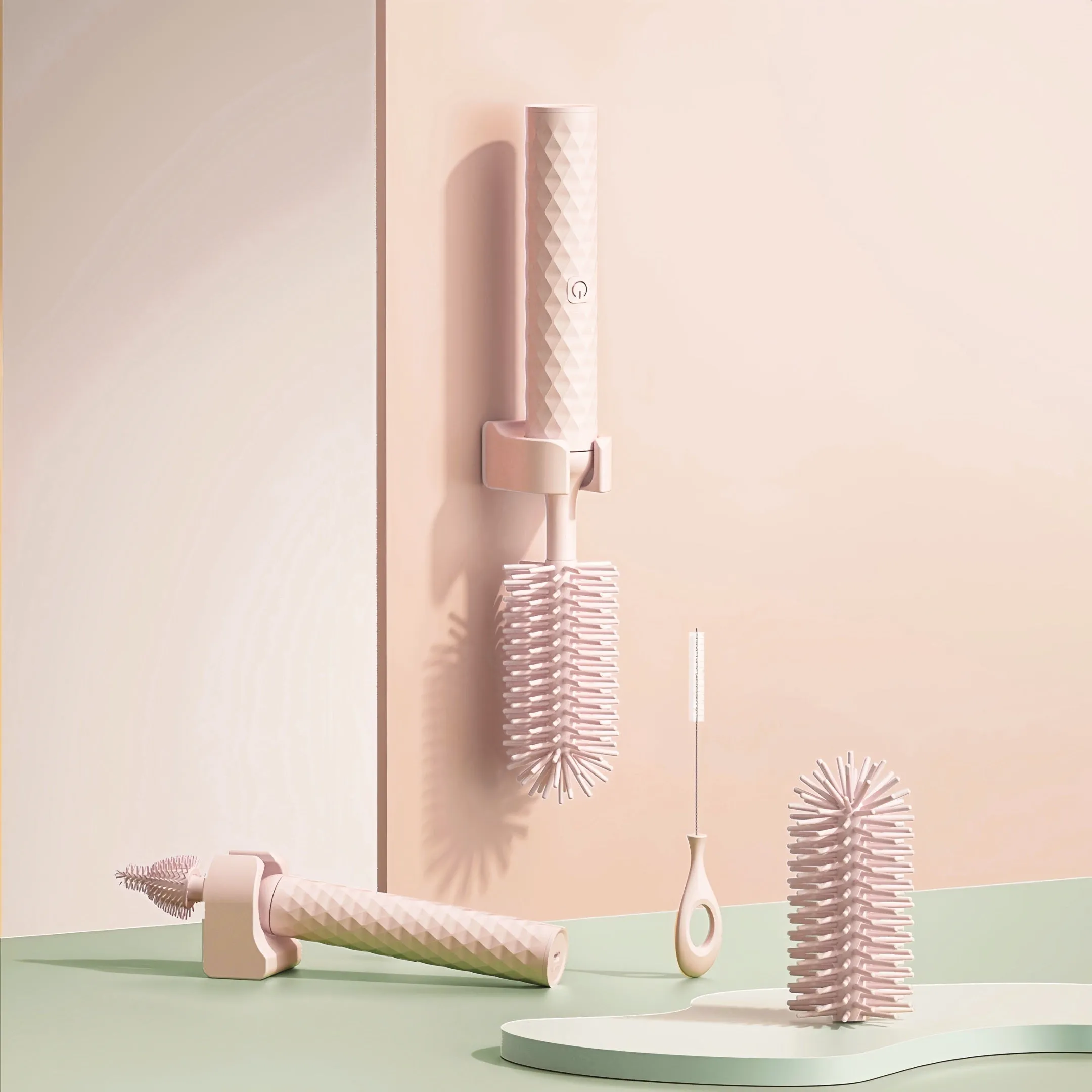 Pink and green electric rotating silicone bottle brush set for cleaning baby bottles and cups.