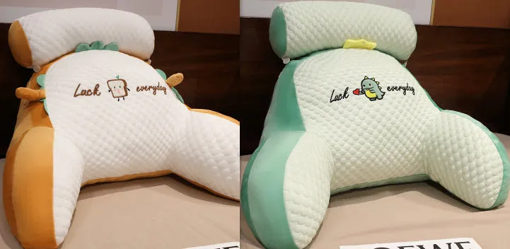 Large triangle-shaped reading cushion with embroidered design on a sofa.