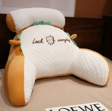 Large triangle-shaped reading cushion with embroidered design on a sofa.