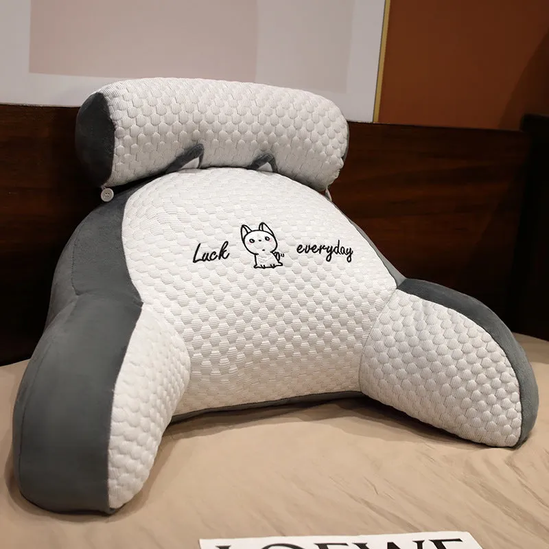Large triangle-shaped reading cushion with embroidered design on a sofa.