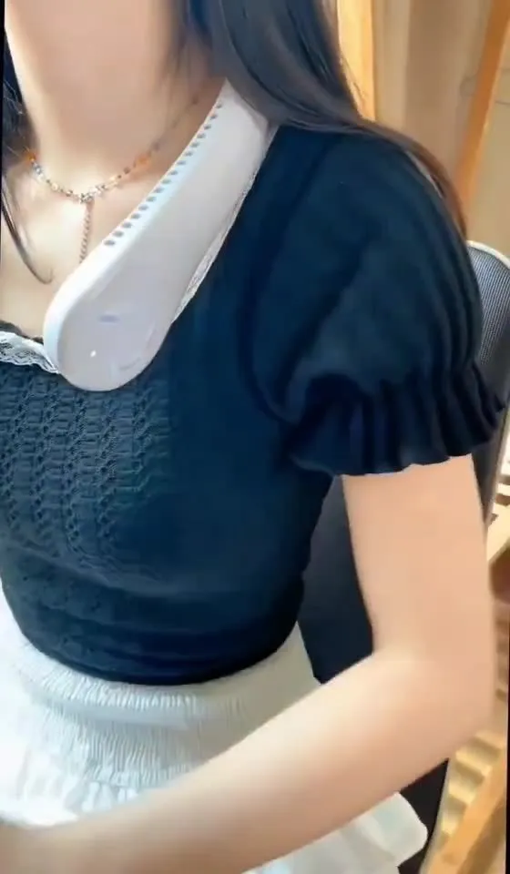 Blue bladeless neck fan hanging around a person's neck, showing the USB charging port and control buttons.