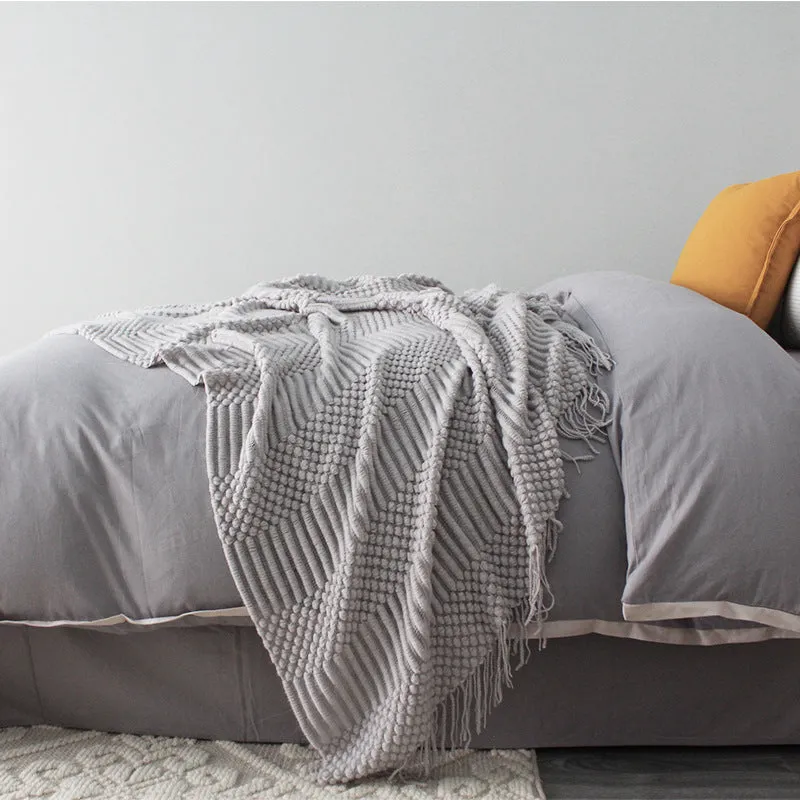 Small grey polyester nap blanket folded, showing its 127x170 cm size on a sofa.