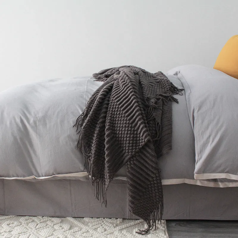 Small grey polyester nap blanket folded, showing its 127x170 cm size on a sofa.
